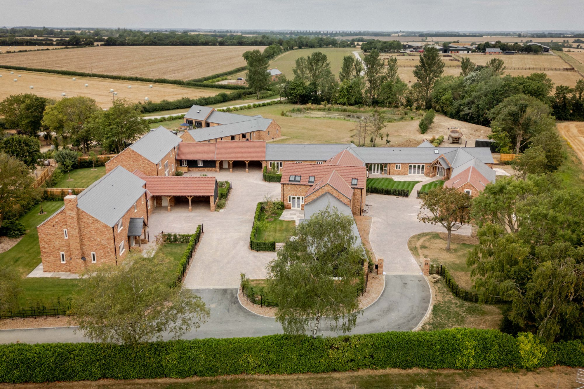 The Old Farmyard from the air: new homes around a farmyard, set among fields and trees