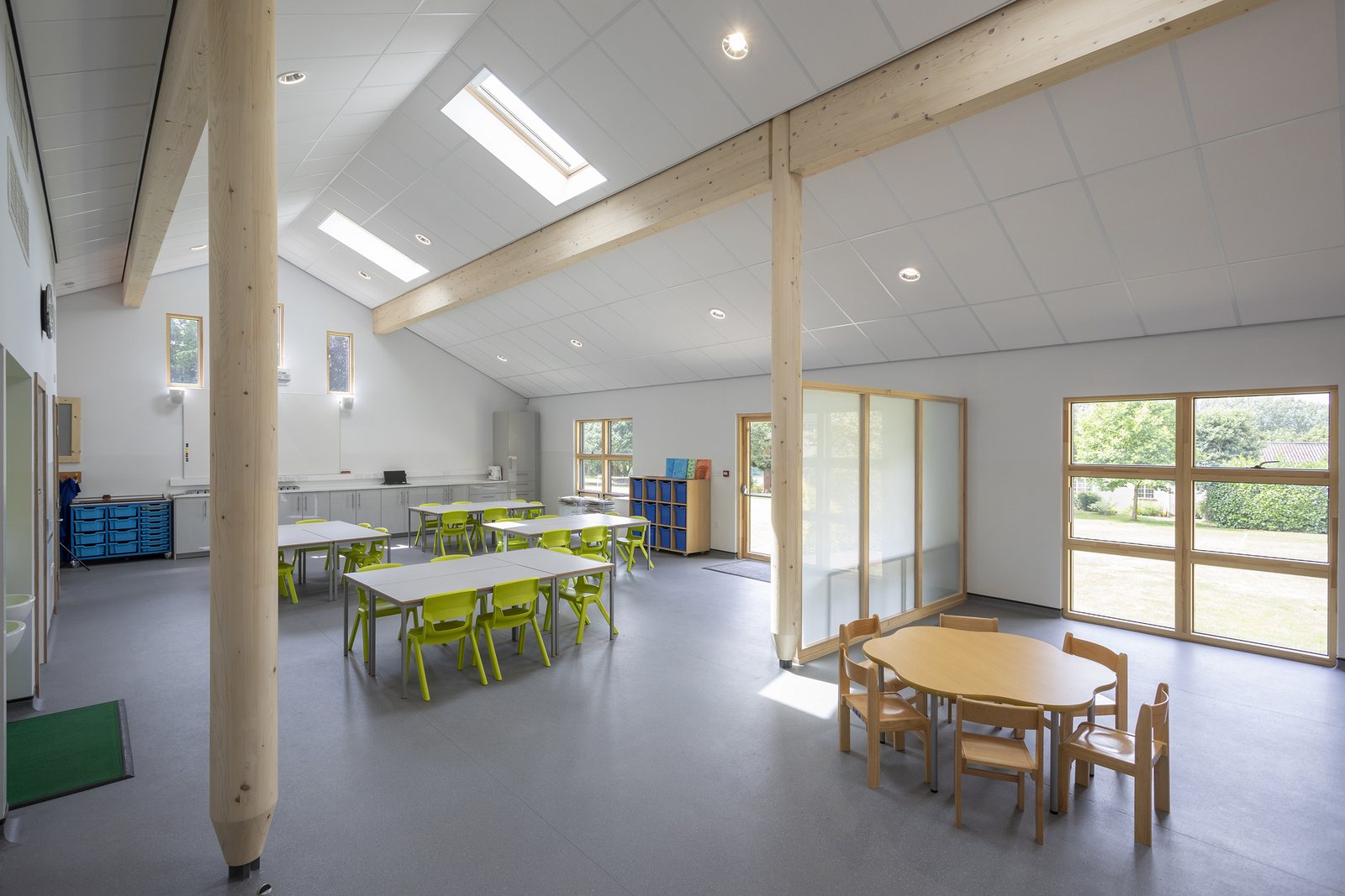 A tall, light classroom with timber columns, exposed beams and rooflights