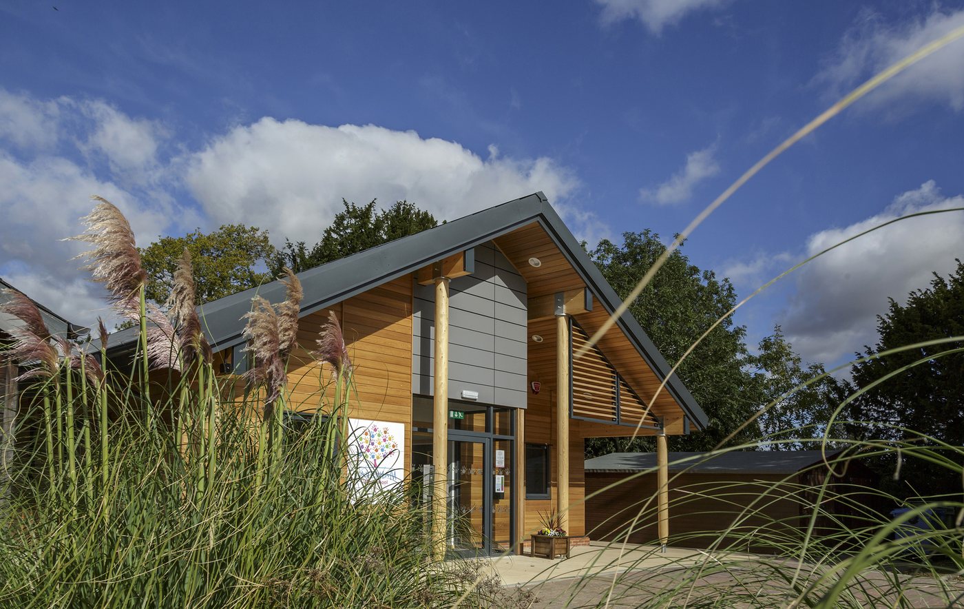 The cedar-clad nursery, its gable and deep timber eaves seen through tall grasses