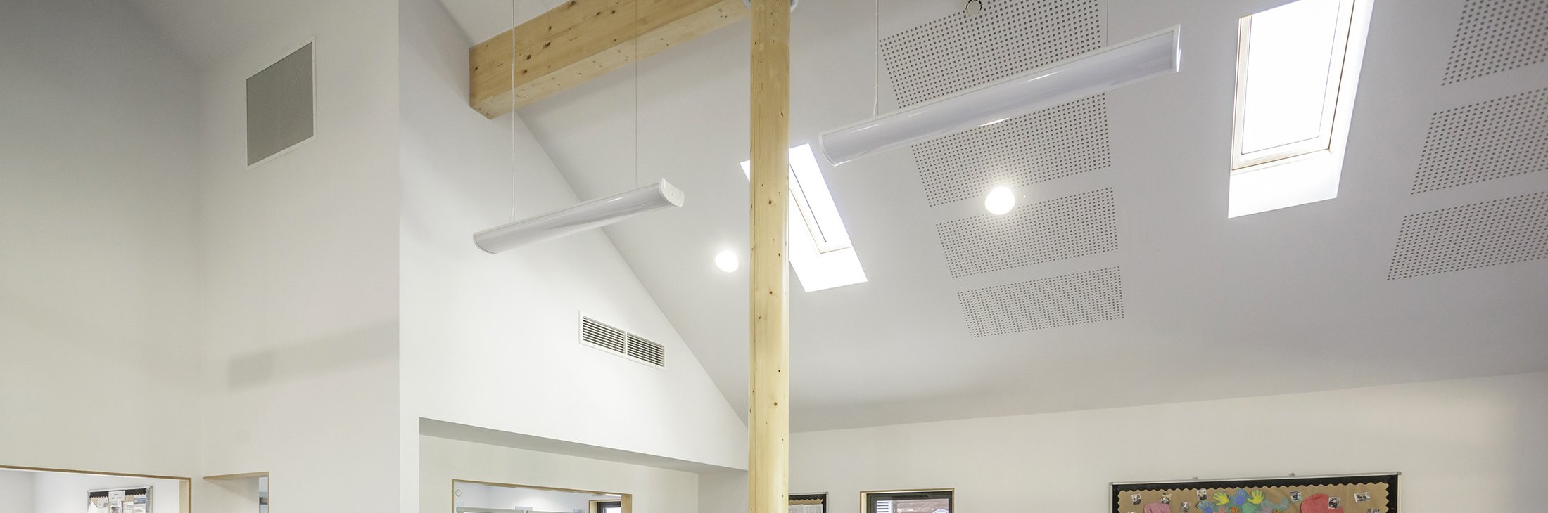 The tall classroom ceiling: rooflights, acoustic panels and a round timber column rising to the glulam beam