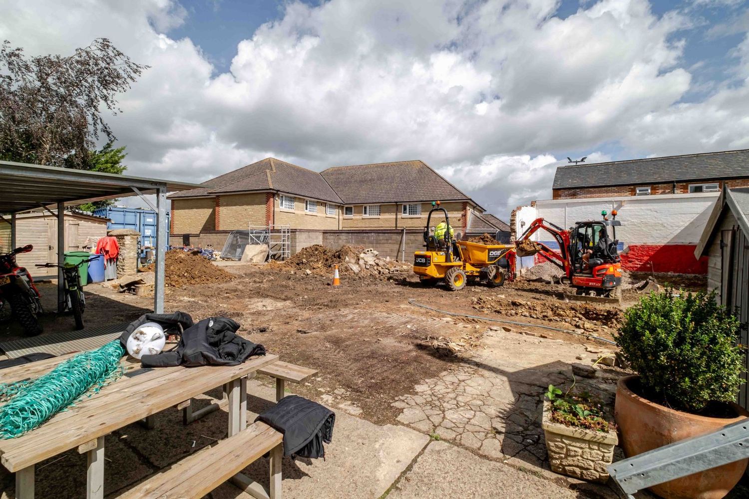 A cleared site with a small excavator, ready for work to begin