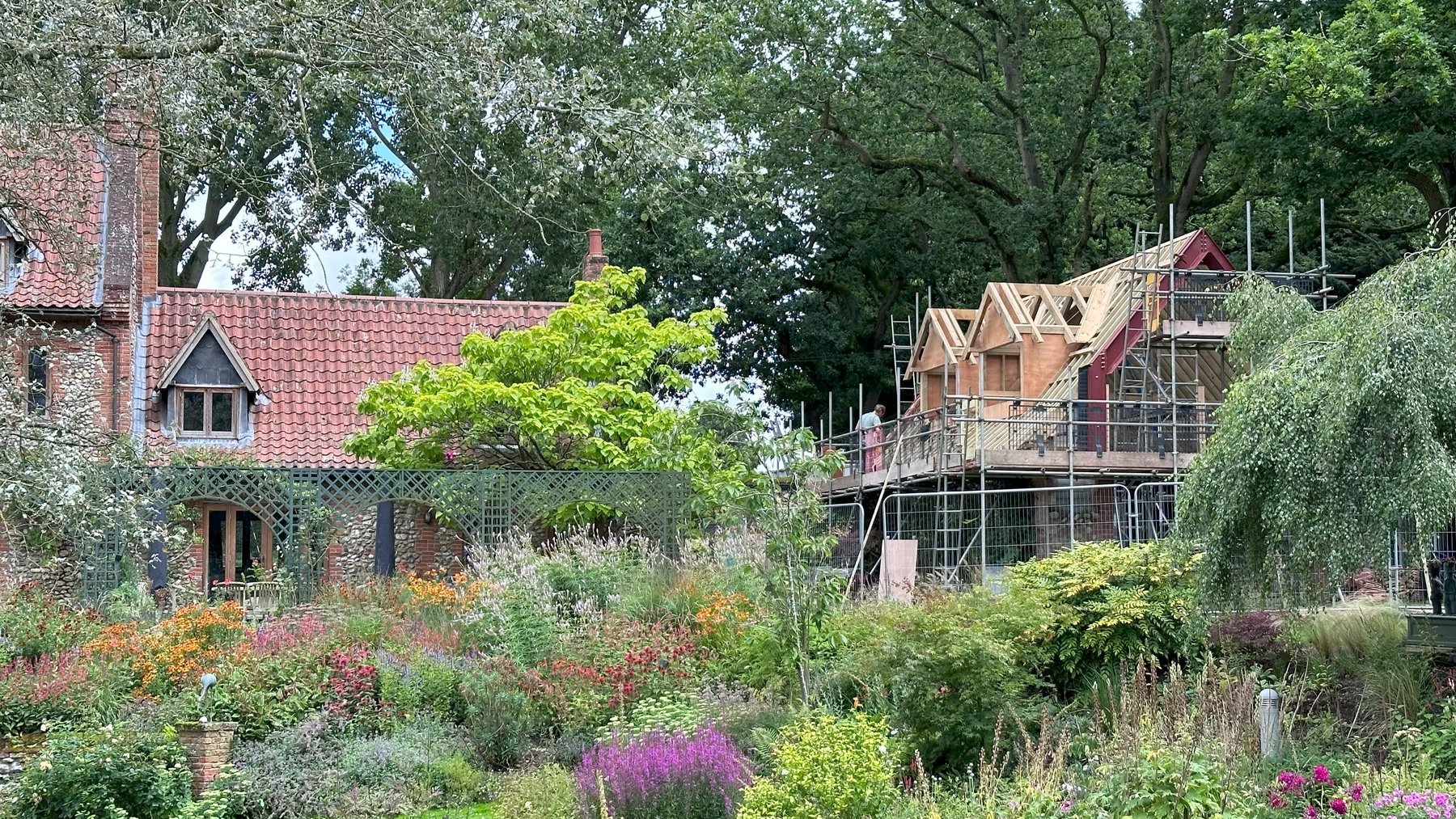 The annexe under scaffold beyond the garden, with the main house to the left
